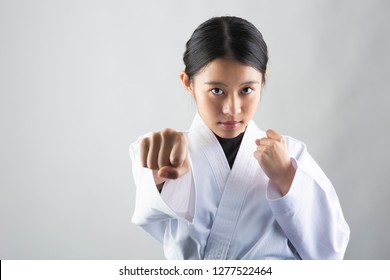 Woman In Karate Suit Performing A Karate Punch On White Background