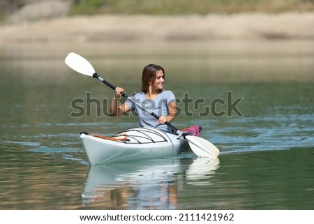 Woman kayaking looking at side in a tranquil lake on summer vacation