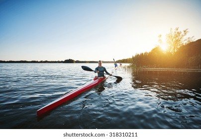 Woman kayaking on a lake while the sun setting - Powered by Shutterstock