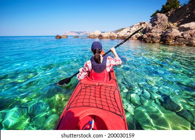 Woman kayaking at sea along the rocky shore of the island. Traveling by kayak.