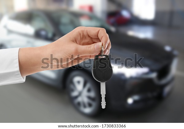 Woman with\
key near new automobile indoors,\
closeup