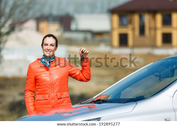 woman with keys in\
hand over the car at home