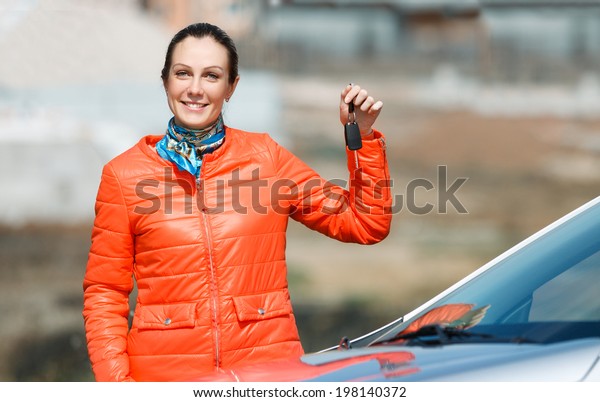 woman with keys in\
hand over the car at home