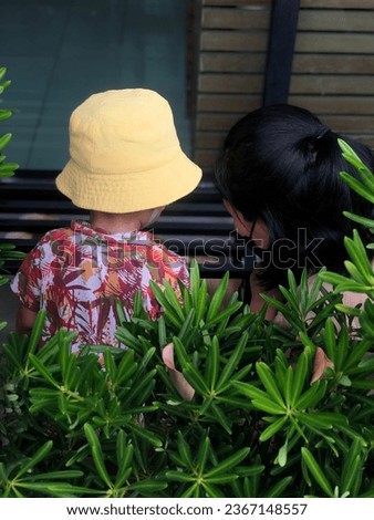A woman with the kid warring hawii shert and yellow hat in the garden cute cutie pretty adorable 
