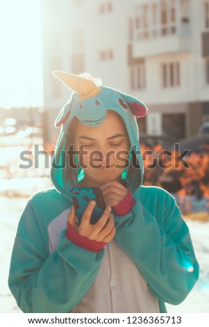 woman in kigurumi unicorn costume use mobile phone with unhappy face  on the street