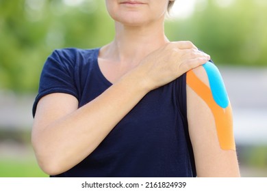 Woman With Kinesio Tape On Her Shoulder. Method Is Purported To Ease Pain And Disability From Athletic Injuries And A Variety Of Other Physical Disorders. Kinesiology, Physical Therapy, Rehabilitation