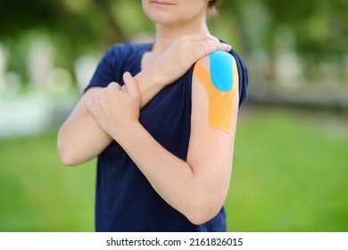 Woman With Kinesio Tape On Her Shoulder. Method Is Purported To Ease Pain And Disability From Athletic Injuries And A Variety Of Other Physical Disorders. Kinesiology, Physical Therapy, Rehabilitation