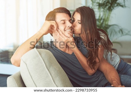 Woman, kiss and man on cheek for couple relax at home in love, intimacy and happy spending time together. Happiness, commitment or trust in relationship with people in living room, affection and care