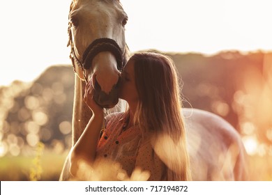 Woman kissing her horse at sunset, autumn outdoors scene - Powered by Shutterstock