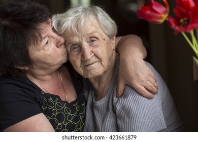 Woman Kissing His Old Mother. Care For The Elderly.