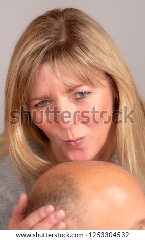 Woman kissing a man's balding head