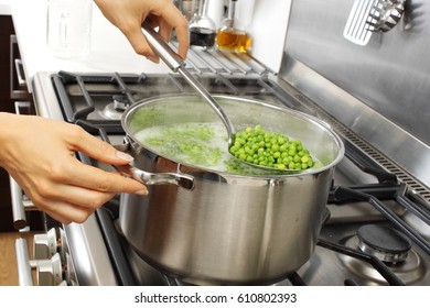 WOMAN IN KITCHEN COOKING PEAS