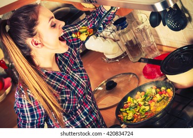 Woman In Kitchen Cooking Stir Fry Frozen Vegetables And Tasting. Girl Frying Making Delicious Dinner Food Meal. Instagram Filtered.