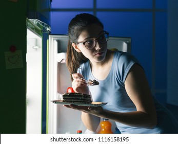 Woman In The Kitchen Having A Late Night Snack, She Is Taking A Delicious Dessert From The Fridge, Diet Fail Concept