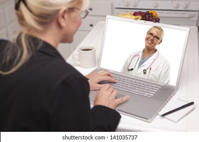 Woman In Kitchen Using Laptop - Online Chat With Nurse Or Doctor On Screen.