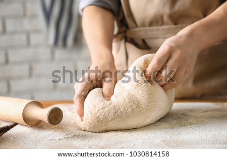 Woman kneading dough on board sprinkled with flour