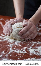 The woman kneads the dough with her hands. Female hands and raw dough on a wooden background. Pizza dough or baked goods. Baking bread, pizza, pasta.