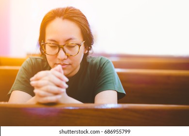 woman knee down and praying in church in the morning.Christian teenager woman hand praying,Hands folded in prayer on the wooden seat in the morning concept for faith, spirituality and religion.