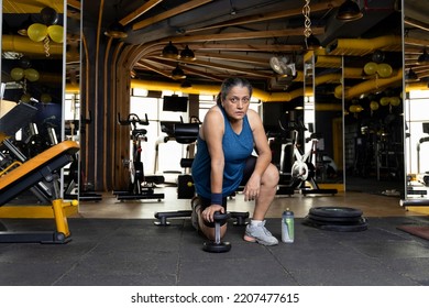 Woman Kneeling On Floor With Dumbbell