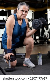 Woman Kneeling On Floor With Dumbbell