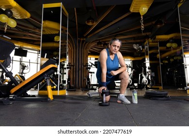 Woman Kneeling On Floor With Dumbbell