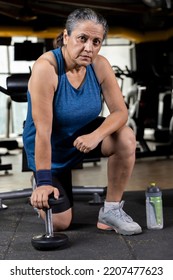 Woman Kneeling On Floor With Dumbbell