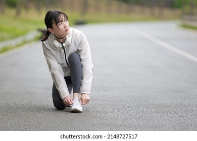 Woman Kneeling And Tying Shoelaces During Exercise.