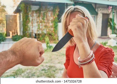 Woman With A Knife In Her Hand Against A Man. Self-defense, Attack, Conflict With A Knife, Aggression Concept.