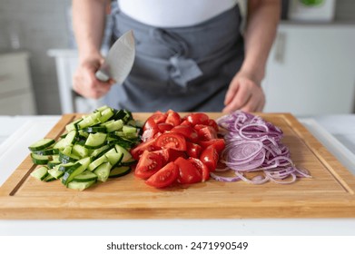 Woman with knife in her hands and chopped vegetables on a cutting board - Powered by Shutterstock