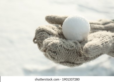 Woman in knitted mittens holding snowball outdoors, closeup