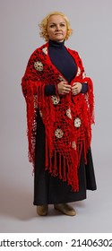 a woman in a knitted red shawl stands in full growth on a white background