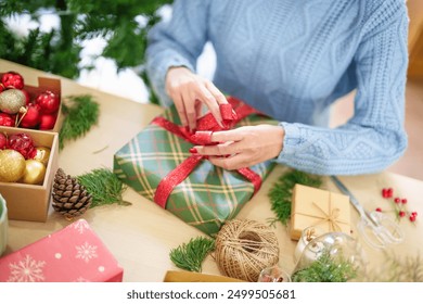 Woman in knitted sweater wrapping christmas presents with eco paper girl packing christmas gifts Xmas holiday concept. - Powered by Shutterstock