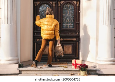 Woman Knocking On Door Of House On Autumn Day