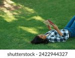 Woman, knowledge and reading book on grass, literature and smiling for fiction or fantasy story. Female person, nature and relaxing on lawn for education, information and student studying in garden