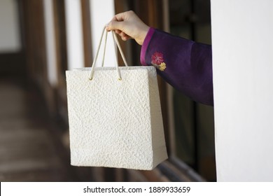 Woman in Korean traditional clothes holding shopping bag
