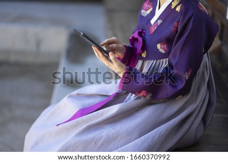 Woman in Korean traditional clothes using digital tablet