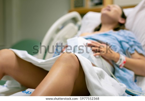 A woman in labor, with\
painful contractions, lying in the hospital bed. Childbirth and\
baby delivery.