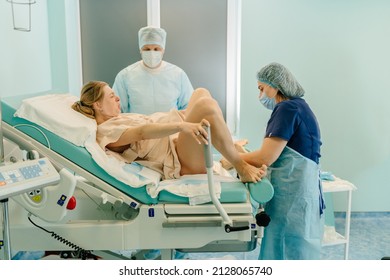 Woman Laboring In Delivery Room With Nurse And Husband Before Birth In Hospital Delivery Room.