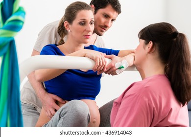 Woman Laboring In Delivery Room With Nurse And Husband