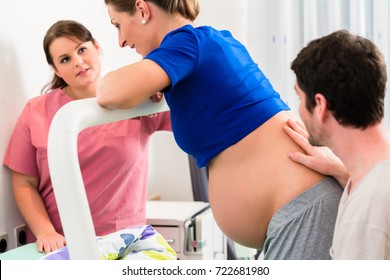 Woman Laboring In Delivery Room With Nurse And Husband Before Birth