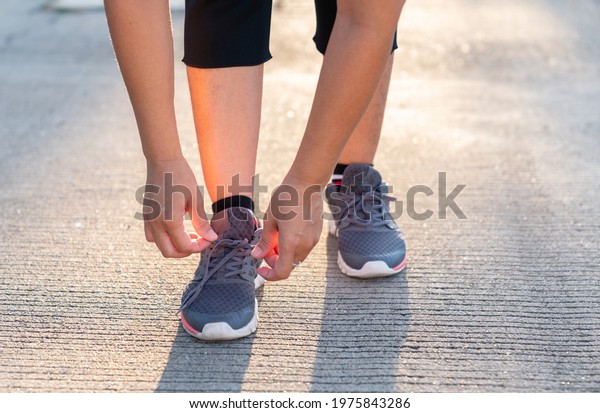 A woman laces her shoes before jogging infront off\
her home.