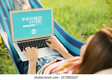 Woman with laptop activating promo code while doing online shopping outdoors