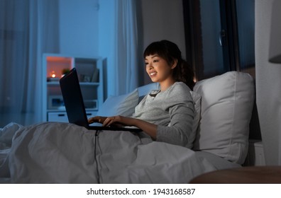 Woman With Laptop In Bed At Home At Night