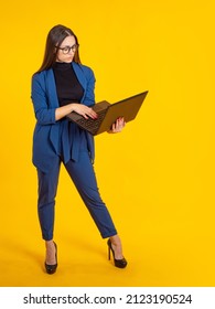 Woman laptop. Girl is standing with computer. Businesswoman vertical portrait. Modern businesswoman in full growth. Businesswoman in autumn suit. Girl with laptop on yellow. Business Style Model