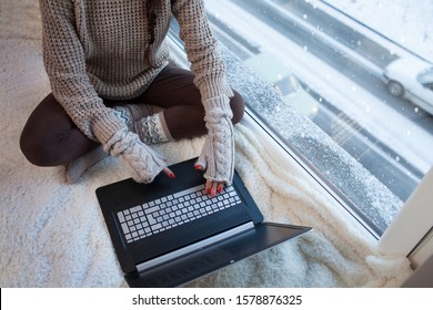 Woman With Laptop And Gloves Sitting Home By The Window. Winter Traffic Outside. Cold And Broken Heating Idea