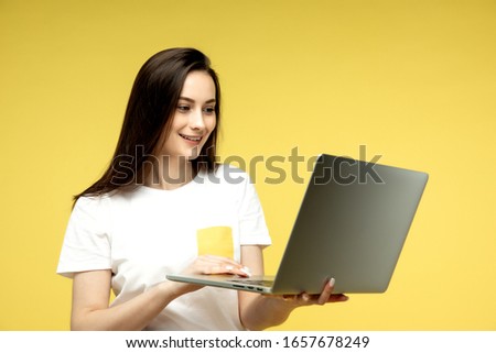 woman with laptop on yellow background, copy space.