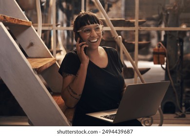 Woman, laptop and phonecall or talking in factory, foundry and inventory for raw materials. Professional, quality control and browsing for service worker for machines, email and booking conversation - Powered by Shutterstock