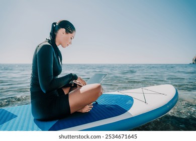 Woman Laptop Stand Up Paddleboard - Working remotely on a stand up paddleboard in the ocean. - Powered by Shutterstock