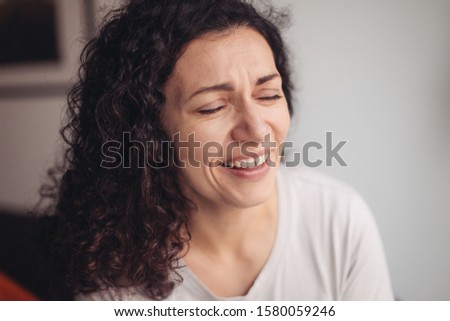 A woman is laughing hard with closed eyes 