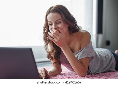 Woman laughing when reading news on laptop, online communication